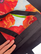 Close-up of red poppy watercolor print on black canvas, showing fabric texture and dark flecks