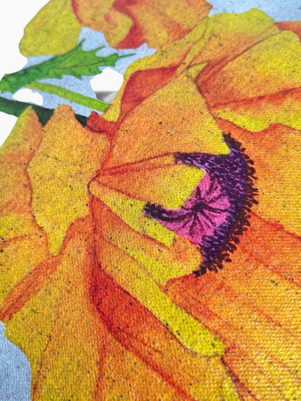 A close-up of black cotton canvas tote with golden poppy print with purple center and small green leaves, displaying the black flecks and texture of the canvas through the print